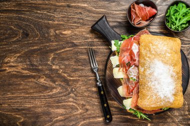 Jamon jambonlu sandviç, yanında roka ve peynirli peynirli ciabatta ekmeği. Ahşap arka plan. Üst Manzara. Boşluğu kopyala