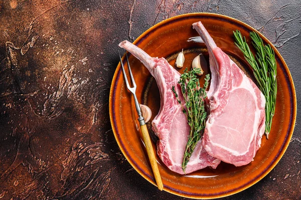 Çiğ domuz pirzolası, et bifteği, biber ve tuz. Karanlık arka plan. Üst Manzara. Boşluğu kopyala