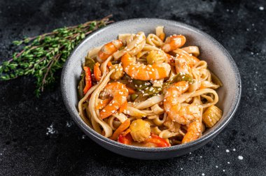 Çin tavasında karides karidesli udon usulü deniz mahsulü erişte. Siyah arka plan. Üst görünüm