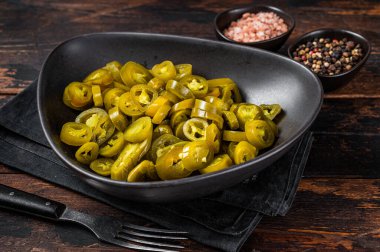 Jalapenos 'u sakladım, turşuyu kurup, tabağa koydum. Karanlık ahşap arka plan. Üst görünüm
