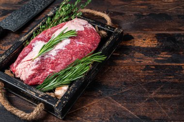 Tahta tepside bıçakla kesilmiş çiğ et eti. Koyu ahşap arka plan. Üst Manzara. Boşluğu kopyala