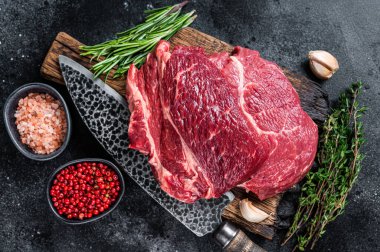 Çiğ Chuck 'ın gözü siyah Angus bifteği kasap tahtasının üzerinde bıçakla yuvarlandı. Siyah arka plan. Üst görünüm