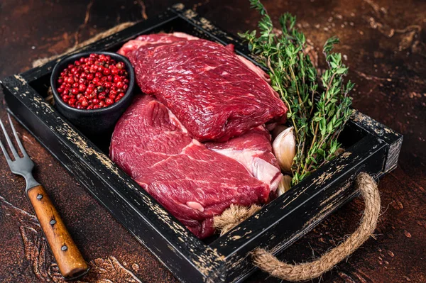 Syrový steak z hovězího žebra v dřevěném tácu s bylinkami. Tmavé pozadí. Horní pohled — Stock fotografie