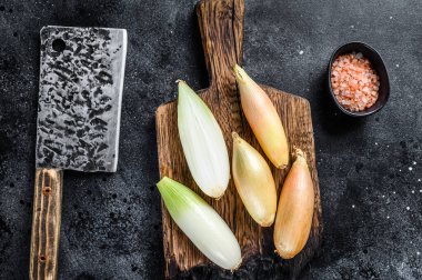 Tahta üzerinde taze çiğ çiğ bebek soğan soğanı soğanı. Siyah arka plan. Üst görünüm