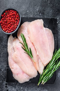 Misket tahtasında çiğ tavuk göğsü fileto bifteği. Siyah arka plan. Üst görünüm