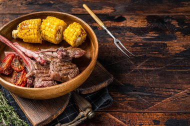 Barbekü kuzu pirzolası, kuzu eti ve ahşap tabakta koyun eti. Koyu ahşap arka plan. Üst Manzara. Boşluğu kopyala