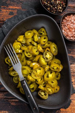 Jalapenos 'u sakladım, turşuyu kurup, tabağa koydum. Karanlık ahşap arka plan. Üst görünüm