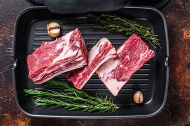 Dana eti, pirzola, et, ızgara tavasında pişmeye hazır. Karanlık arka plan. Üst görünüm