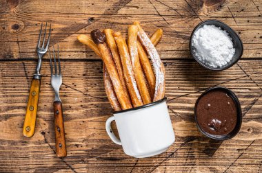 Şeker ve çikolata soslu Churros. Ahşap arka plan. Üst görünüm