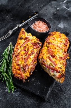 Jambonlu, pastırmalı, sebzeli ve peynirli sıcak açık baget sandviç. Siyah arka plan. Üst görünüm