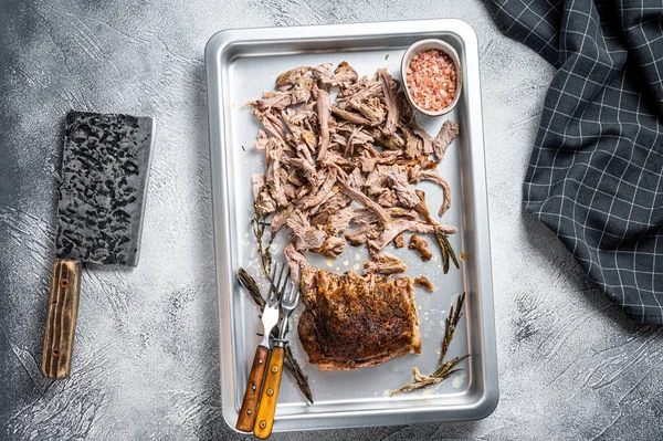 Texas bbq smoked puilled pork meat in a steel baking tray. White background. Top view