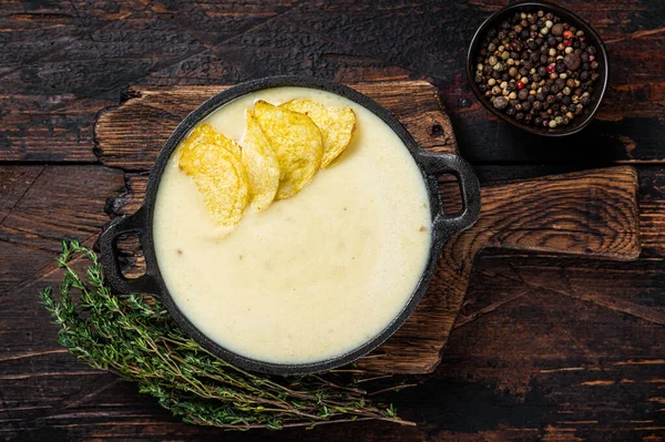 Sopa de crema de patata con papas fritas en sartén sobre tabla de madera. Fondo de madera oscura. Vista superior —  Fotos de Stock