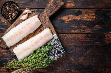 Çiğ morina fileto bifteği ve kasap satırı. Koyu ahşap arka plan. Üst Manzara. Boşluğu kopyala