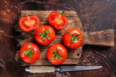 Tahta kesme tahtasıyla kırmızı kiraz domateslerini kes. Karanlık arka plan. Üst görünüm