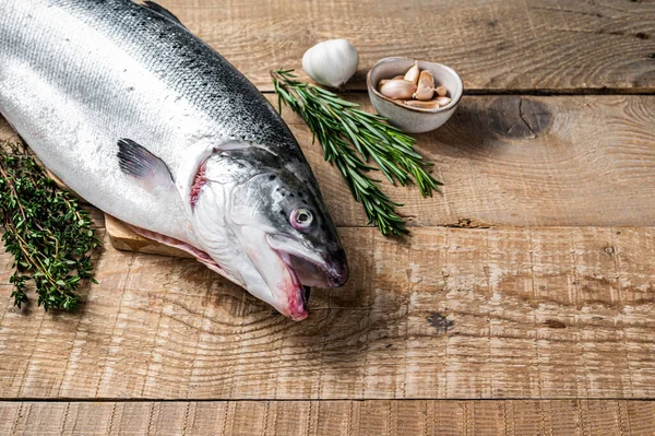 Raw marine salmon fish on a wooden kichen table with herbs. Wooden background. Top view. Copy space — Stock Photo, Image