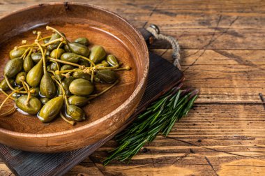 Tahta bir tabakta sirke içinde tuzlanmış kapari. Ahşap arka plan. Üst Manzara. Boşluğu kopyala