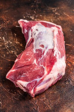Kemiğin üzerinde çiğ koyun eti var. Karanlık arka plan. Üst görünüm