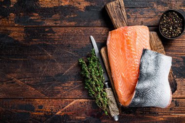 Ahşap bir tahtanın üzerinde otlar ve tuzlu somon fileto balığı. Koyu ahşap arka plan. Üst Manzara. Boşluğu kopyala