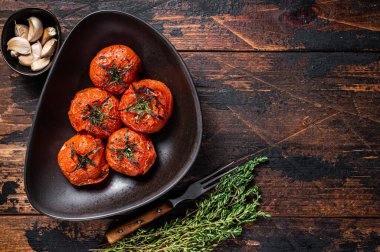 Fırında kavrulmuş kiraz domatesli kekik ve sarımsaklı bir tabak. Koyu ahşap arka plan. Üst Manzara. Boşluğu kopyala