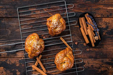 Ev yapımı taze tarçınlı çörek veya rulo, İsveç Kanelbullar. Koyu ahşap arka plan. Üst görünüm