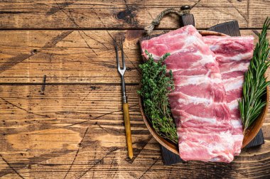 Et çatalıyla ahşap tabakta çiğ domuz pirzolası. Ahşap arka plan. Üst Manzara. Boşluğu kopyala