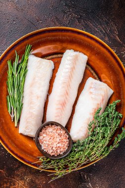 Çiğ morina fileto bifteği, kekik ve tuzlu kırsal tabakta. Karanlık arka plan. Üst görünüm