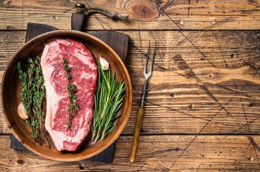 Taze New York bifteği ya da ahşap bir tabakta otlarla pişirilmiş çizgili biftek. Ahşap arka plan. Üst Manzara. Boşluğu kopyala