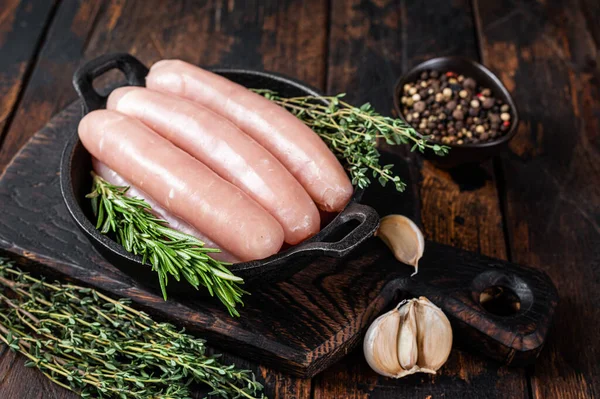 Pork raw sausages in a pan with herbs. Dark wooden background. Top view — Stock Photo, Image
