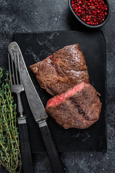 Grillé Top Blade ou plat steaks de viande de rôti de bœuf en fer sur panneau de marbre. Fond noir. Vue du dessus — Photo