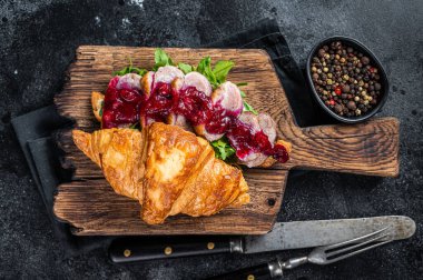 Ördek göğsü dilimleri, roka ve soslu kruvasan sandviçi. Siyah arka plan. Üst Görünüm