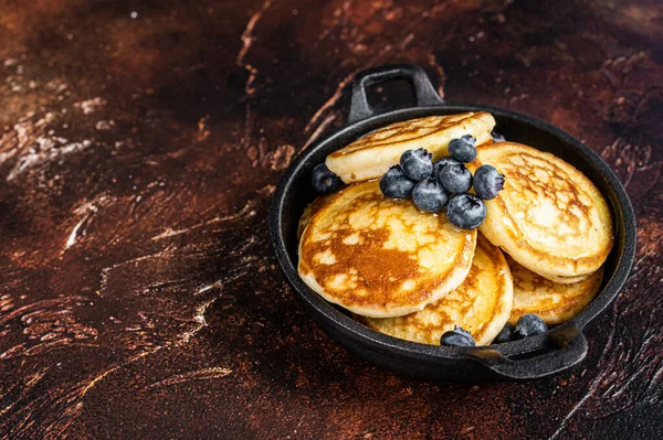 Pancake goreng dengan blueberry segar dan sirup maple dalam panci. Latar belakang gelap. Top View. Salin ruang — Stok Foto