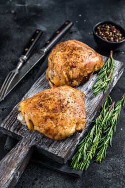 Baharatlı ızgara tavuk butları ahşap bir tahtanın üzerinde biberiyeli. Siyah arka plan. Üst Görünüm