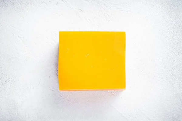 Cheddar sajt tömb a konyhaasztalon. Fehér háttér. Felülnézet — Stock Fotó