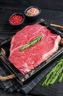 Tahta tepside otlu biftekler için çiğ biftek fileto. Siyah ahşap arka plan. Üst görünüm