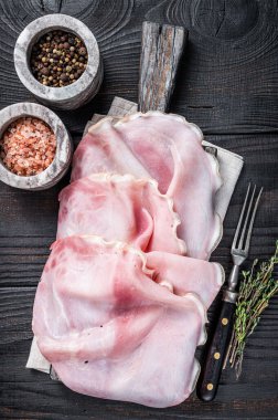 Tahtada otlarla dilimlenmiş jambon. Siyah ahşap arka plan. Üst görünüm