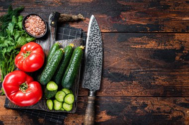 Domatesli yeşil sebze salatası, salatalık, maydanoz, otlar. Koyu ahşap arka plan. Üst Manzara. Boşluğu kopyala