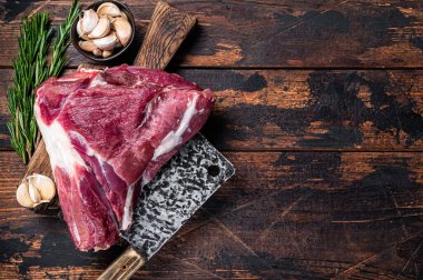 Et satırıyla kasap panosunda pişmemiş çiğ koyun budu. Koyu ahşap arka plan. Üst Manzara. Boşluğu kopyala