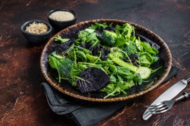Taze roka yapraklı sağlıklı sebze salatası, marul, vegan salatası için ıspanak. Karanlık arka plan. Üst görünüm