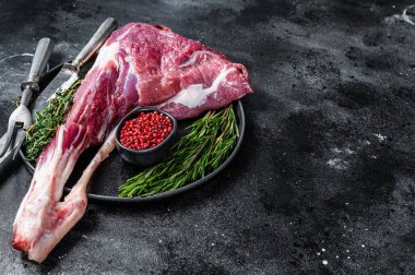 Kemiğin üzerinde çiğ kuzu eti ve otlar. Siyah arka plan. Üst Manzara. Boşluğu kopyala