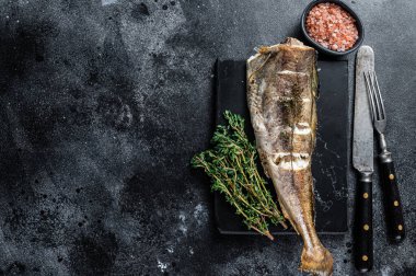 Misket tahtasında kekik olan kızarmış morina balığı. Siyah arka plan. Üst Manzara. Boşluğu kopyala