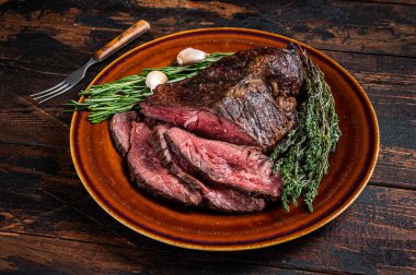 Kavrulmuş askı ya da Onglet dilimlenmiş sığır eti bifteği ve satırla birlikte kırsal bir tabakta. Koyu ahşap arka plan. Üst Görünüm