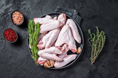 Çiğ ördek kanatları ve şifalı otlar. Siyah arka plan. Üst görünüm