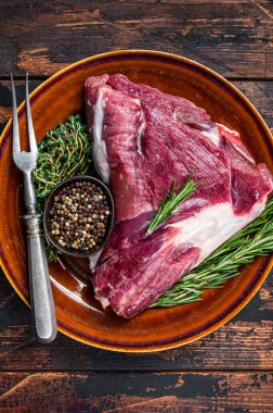 Pişmemiş çiğ keçi budu ya da biberiyeli bacak ve kekik kırsal tabakta. Koyu ahşap arka plan. Üst Manzara. Boşluğu kopyala