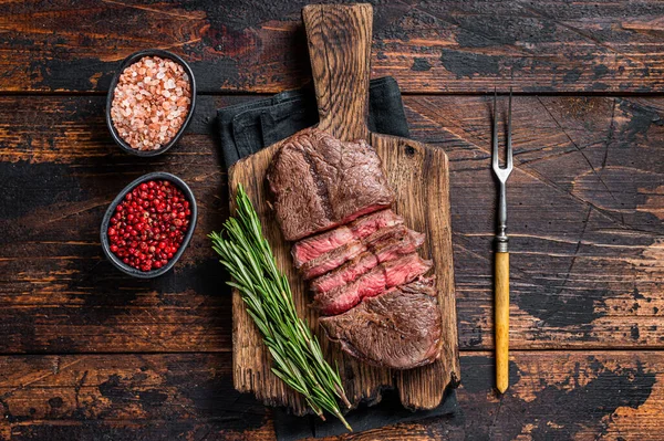 Smažené Top Blade nebo ploché hovězí steaky na dřevěné desce s rozmarýnem. Tmavé dřevěné pozadí. Pohled nahoru — Stock fotografie