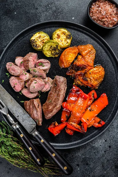 ラム肉やヤギのヒレ肉を焼き野菜とプレートに肉ステーキ.黒い木製の背景。トップ表示 — ストック写真