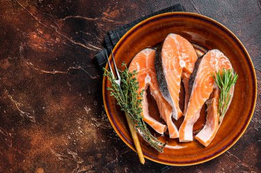 Kırsal tabakta çiğ somon bifteği ve otlar. Karanlık arka plan. Üst Manzara. Boşluğu kopyala