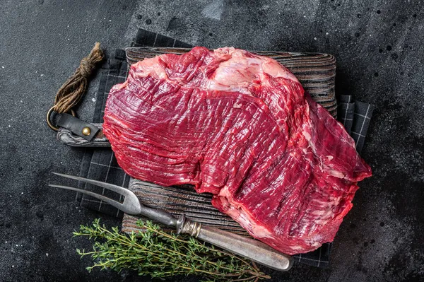 Okokt rått flankkött eller flaxbiff på slaktarbordet. Svart bakgrund. Ovanifrån — Stockfoto