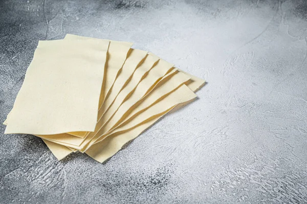 Rohe Lasagneblätter stapeln sich auf einem Küchentisch. Weißer Hintergrund. Ansicht von oben. Kopierraum — Stockfoto