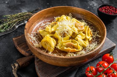 İtalyan ravioli makarnasıyla Mozzarella peyniri ve ahşap tabakta domates. Siyah arka plan. Üst görünüm