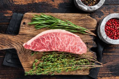 Wagyu A5 çiğ but ya da sığır filetosu, kasap tahtasında kobe eti. Koyu ahşap arka plan. Üst görünüm